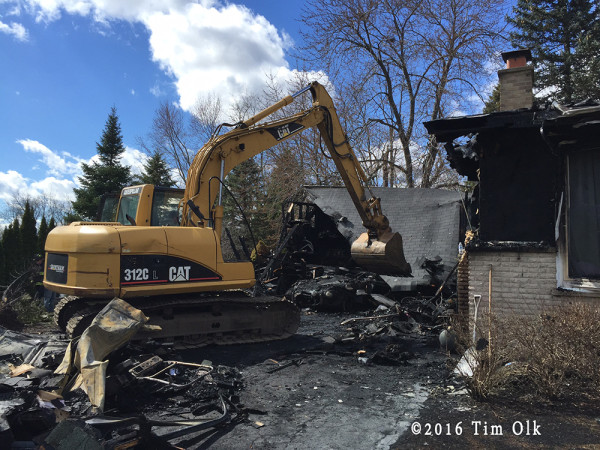 excavator clears debris from house fire