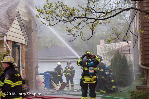firefighters with hose line at fire scene