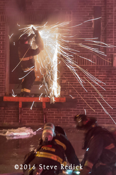 firefighter cuts metal door at night