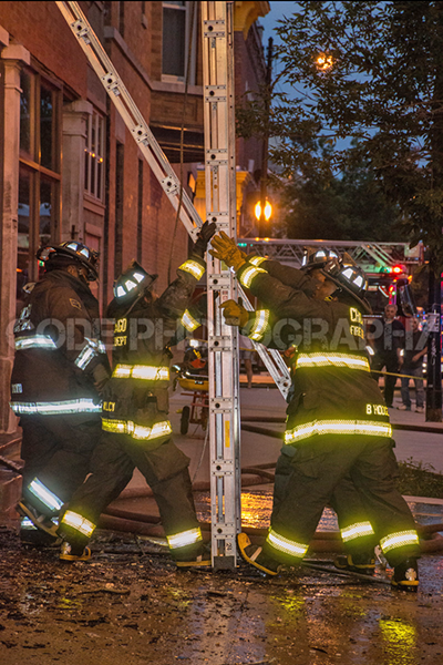 firefighters raise ground ladder at night