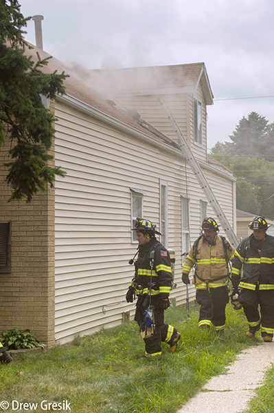 firefighters survey house fire scene
