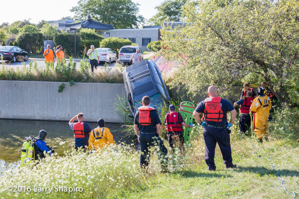 fire department divers view a car on a retaining wall with the driver inside