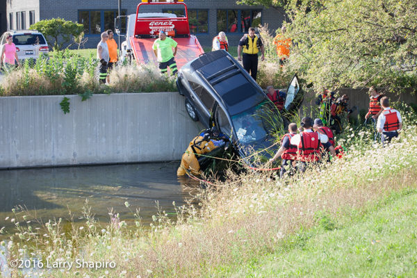 fire department divers remove the driver from a car on a retaining wall 