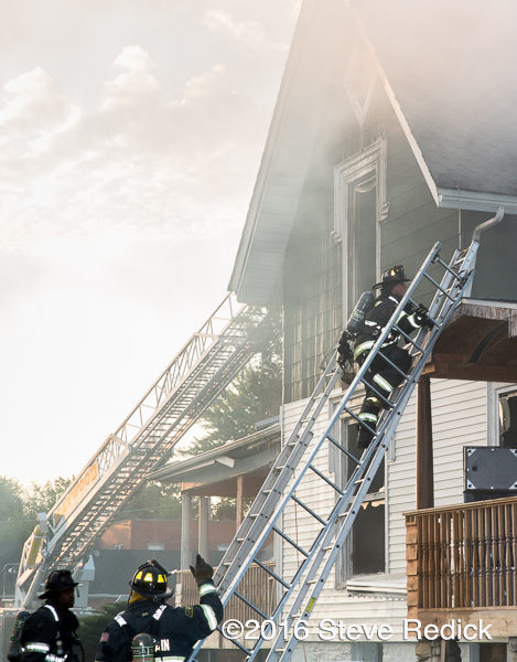 firefighters climb ground ladder at fire
