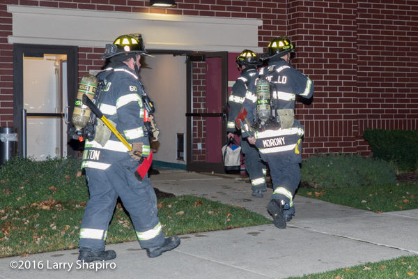 firefighters with tools and PPE enter building
