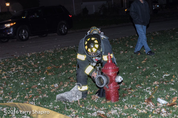 firefighter hooks hose to hydrant at night