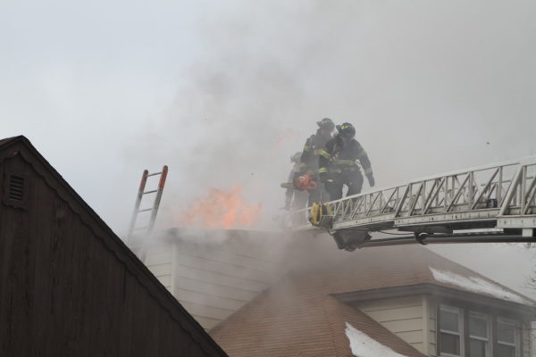 Firefighters on aerial ladder with flames