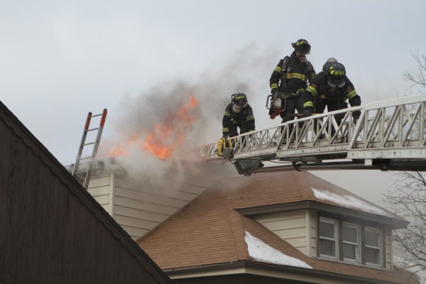 Firefighters on aerial ladder with flames