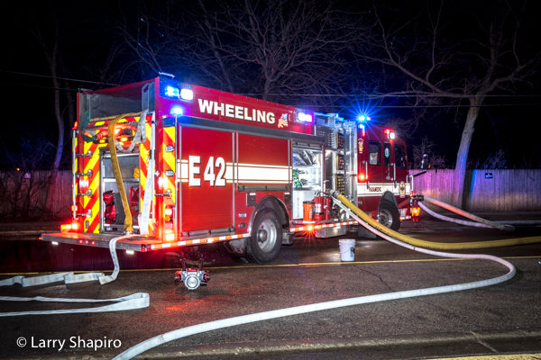 Rosenbauer America Commander fire engine at night fire scene with lights and hose lines