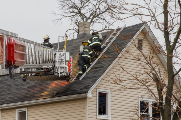 firefighters overhaul roof after house fire