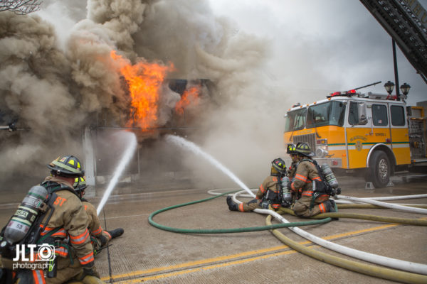 firefighters in street battle fire with which smoke and flames