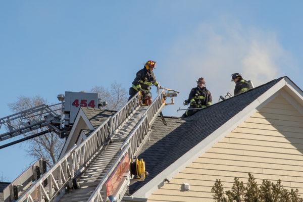 firefighters on roof of fire building