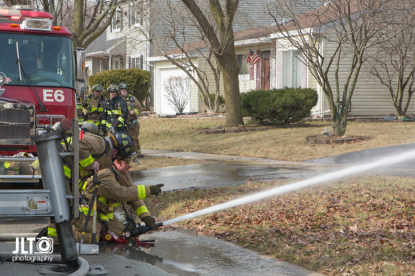 firefighters spray water on house fire