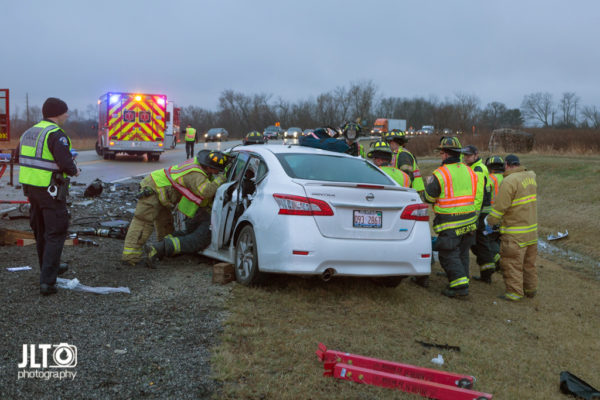 firefighters work to free occupants trapped in a car