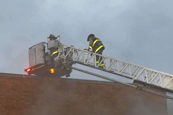 Firefighters ascend tower ladder to the roof