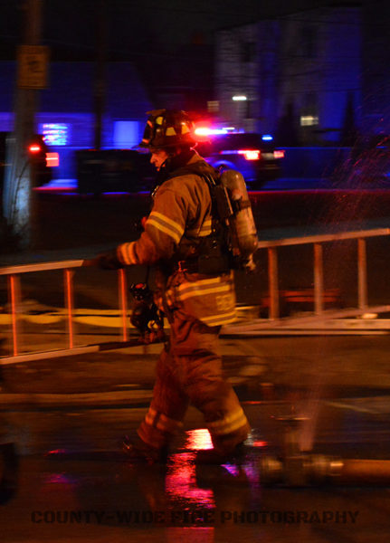 firefighter carrying a ladder at night