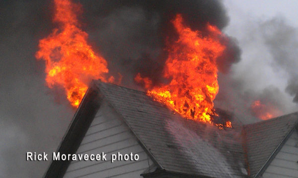 flames burn the the roof of a house