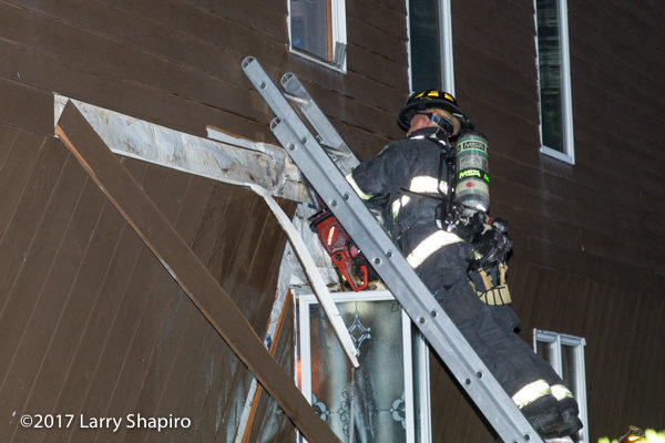 Firefighter cuts siding on a house