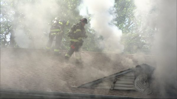 firefighters vent roof with heavy smoke