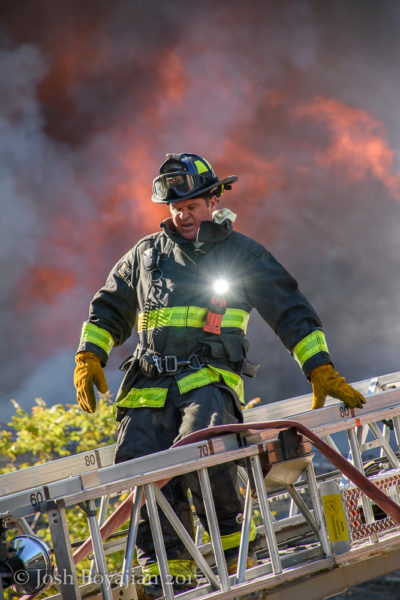 firefighter descends aerial ladder with fire