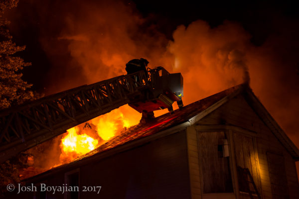 firefighter in tower ladder bucket against heavy fire