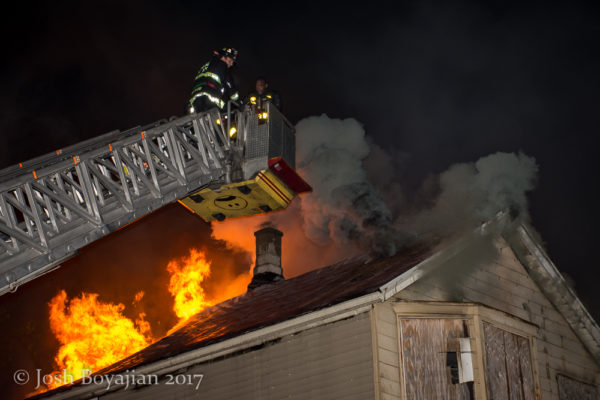 firefighter in tower ladder bucket against heavy fire