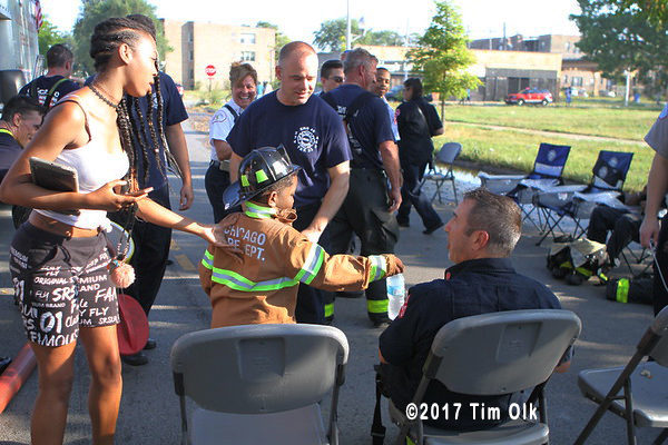 young boy offers a drink to a firefighter
