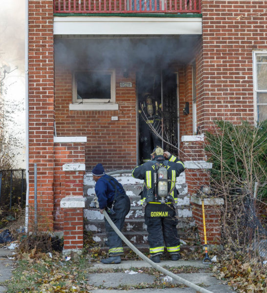 firefighters bring hose to door of house fire