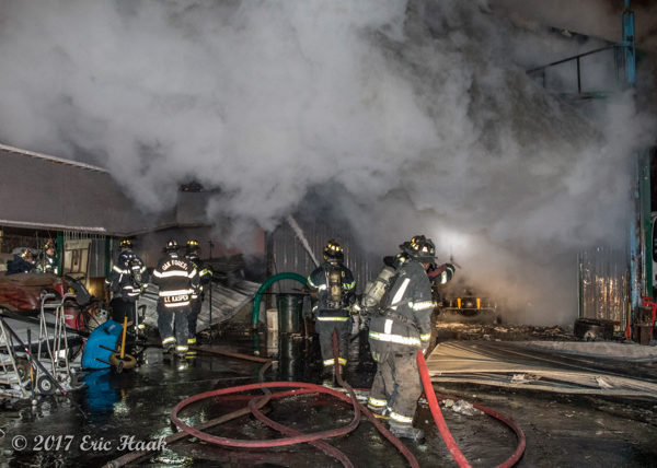 multiple firefighters handle large hose