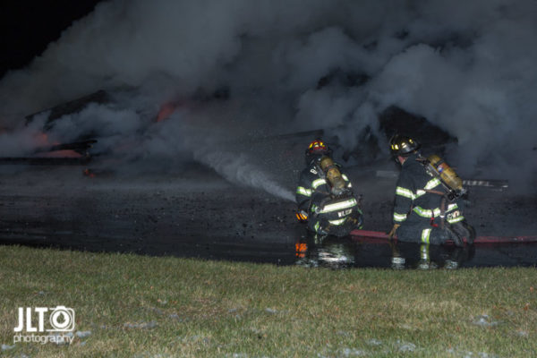 firefighters with hose line at night fire scene