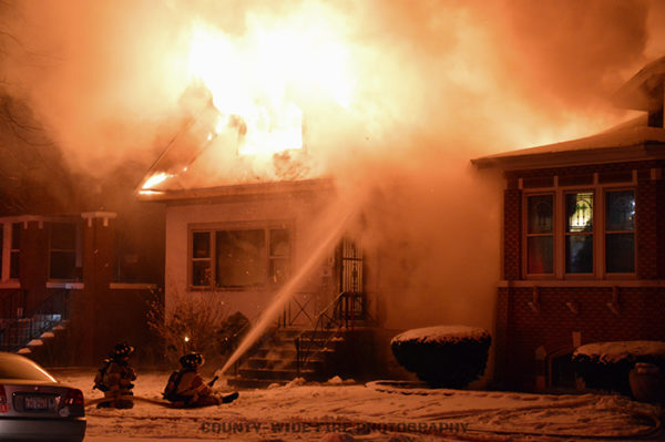 firefighters battle flames that engulfed a house at night
