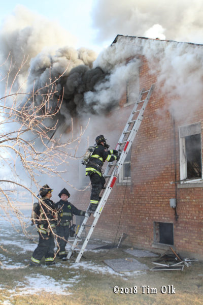firefighter on ladder with heavy smoke
