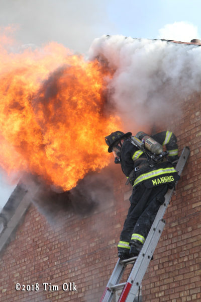 firefighter on ladder with flames