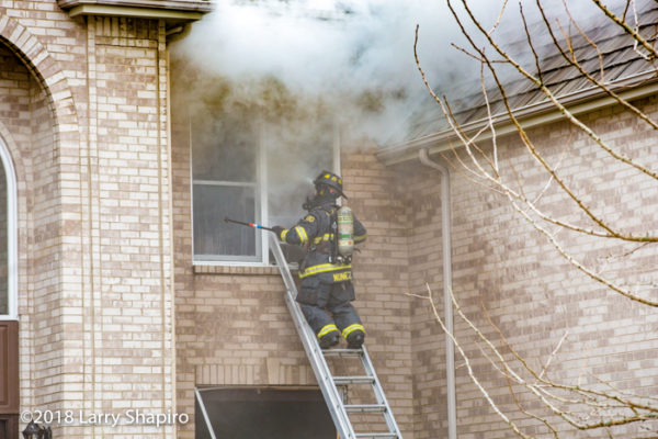 Firefighter on ladder with heavy smoke