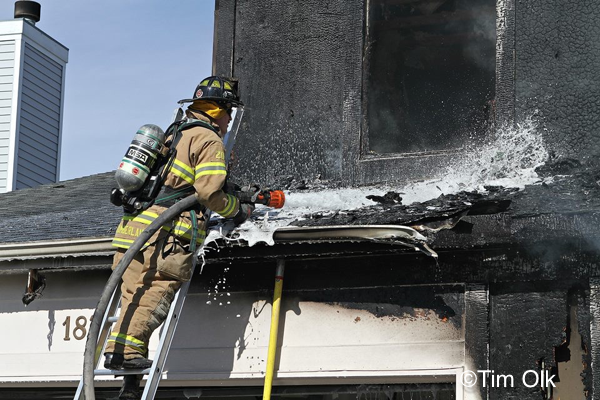 Firefighter washes down a roof after a house fire