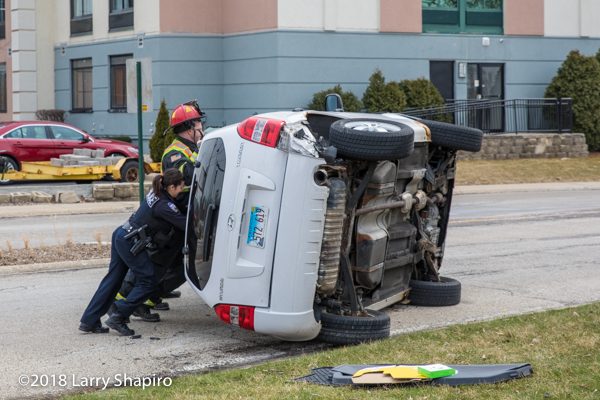 police officers and Firefighters roll car onto the wheels