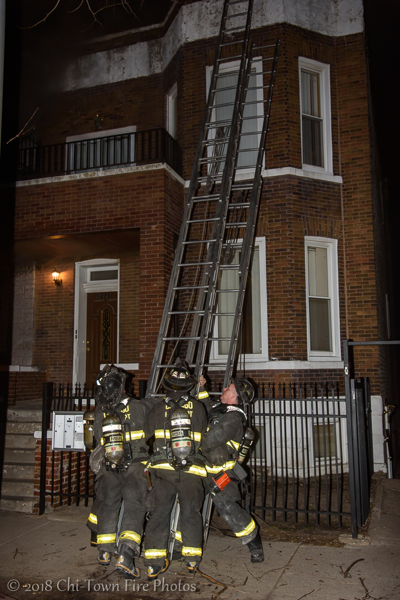 Firefighters raise ladder at fire scene