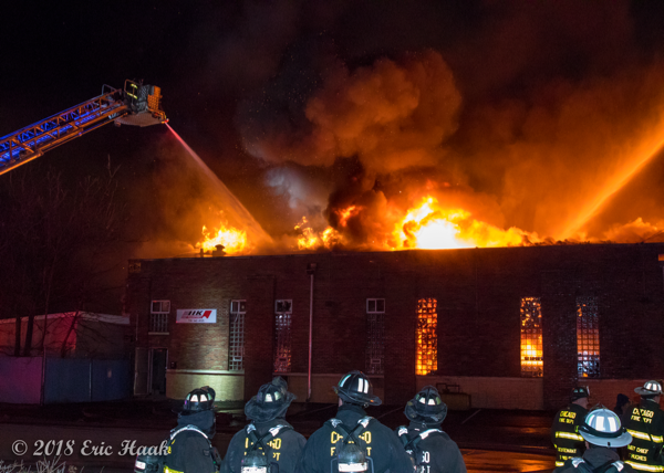 massive fire burns through warehouse roof at night
