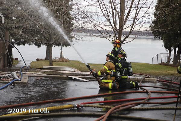 Firefighters with hose line battle a fire