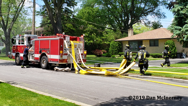 Firefighters pull hose from fire engine