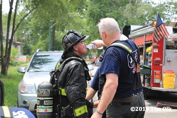 Firefighter receives hydration after a fire on a hot day