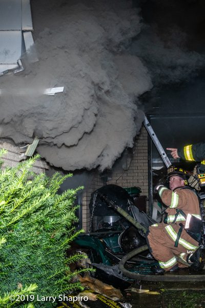heavy smoke curls around house siding at night fire scene